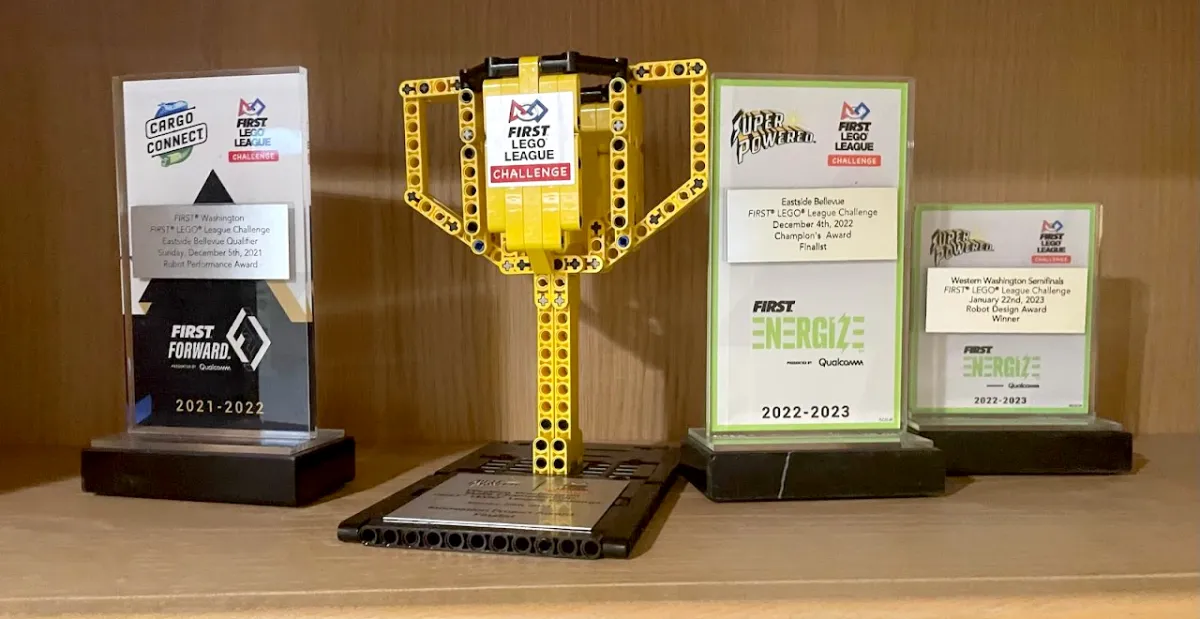 Four FIRST LEGO League trophies and plaques on a shelf, from the 2021-22 and 2022-23 seasons