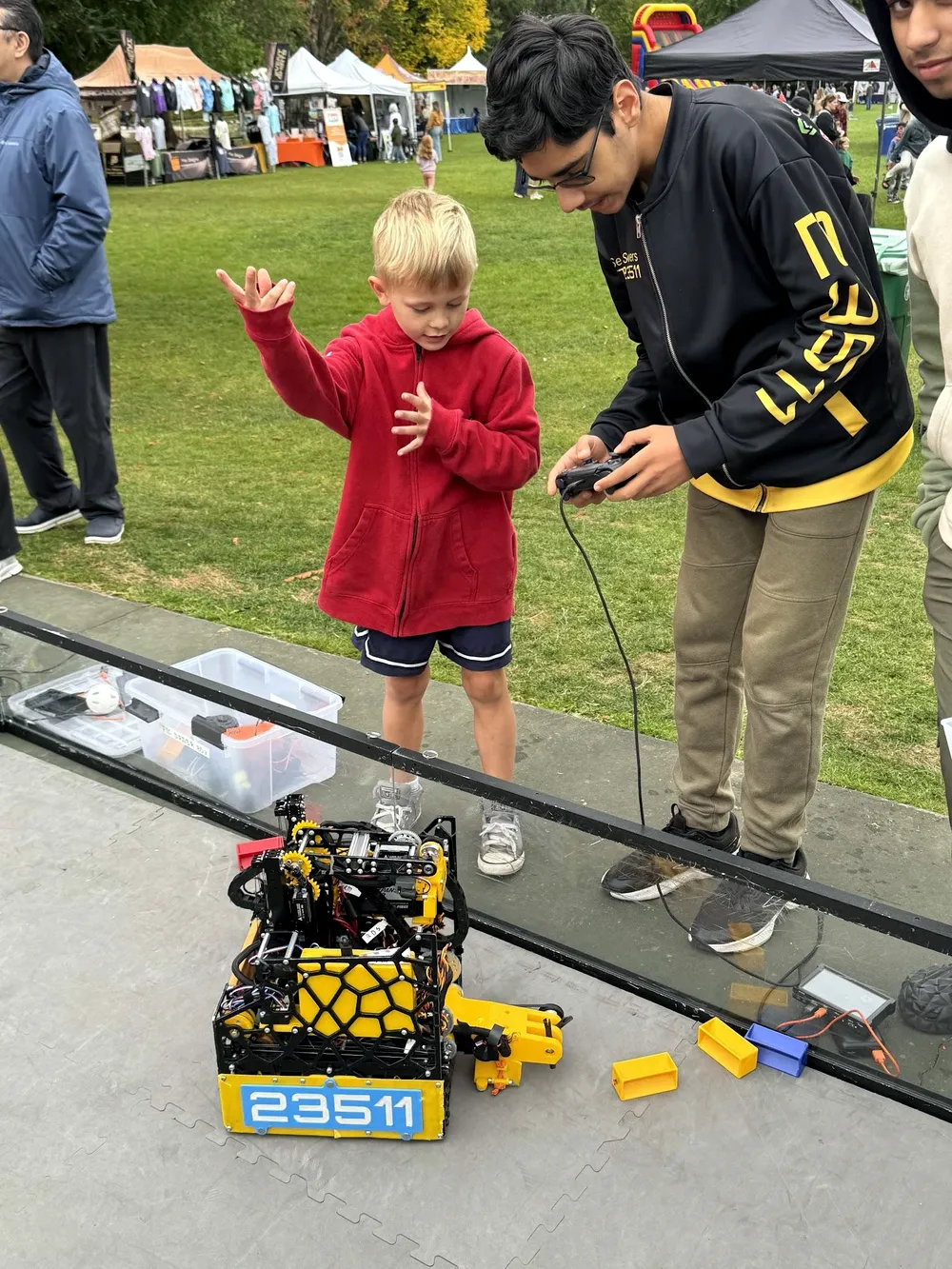 A team member showing a young child the robot at the Salmon Days festival