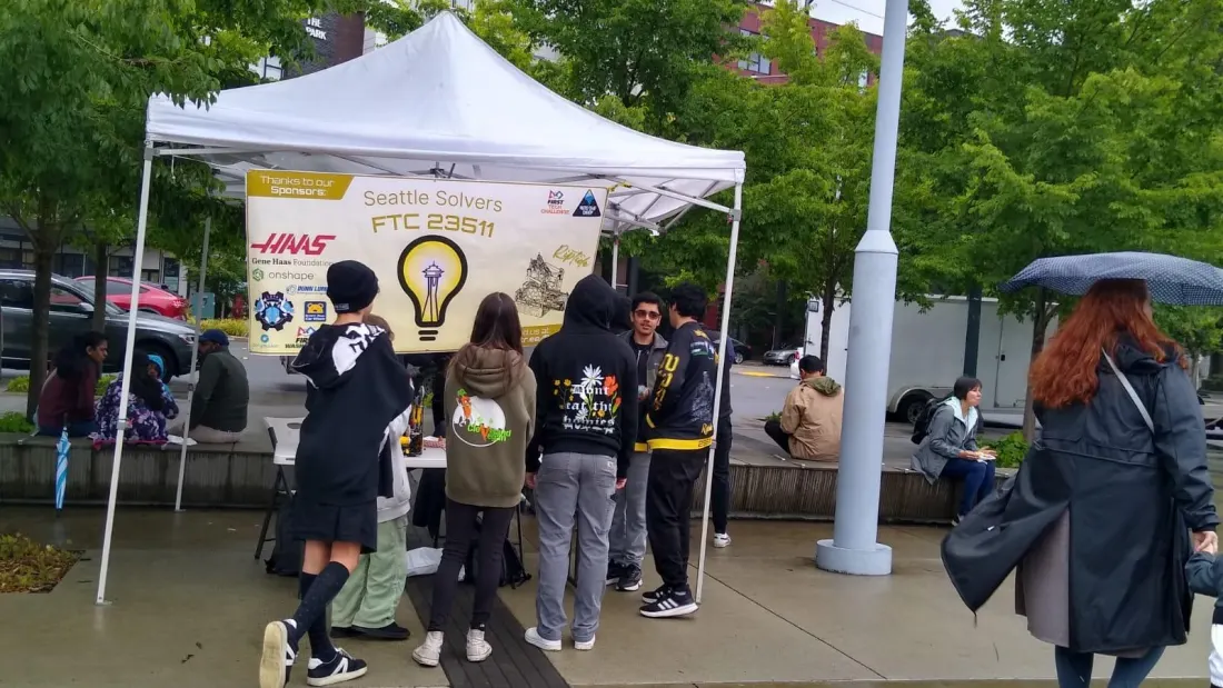 Team members and visitors at the Seattle Solvers tent, under the team banner, at VegFest