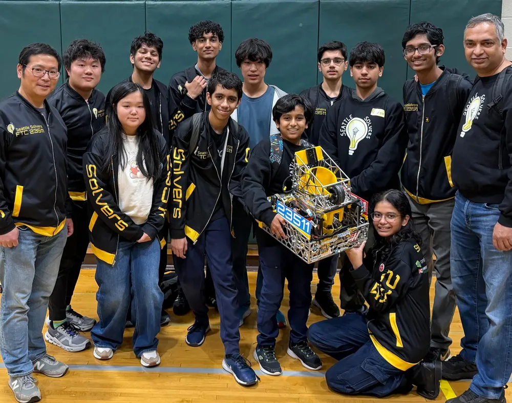 The team and two coaches gathered around Cypher, one student holding the robot up in front of them