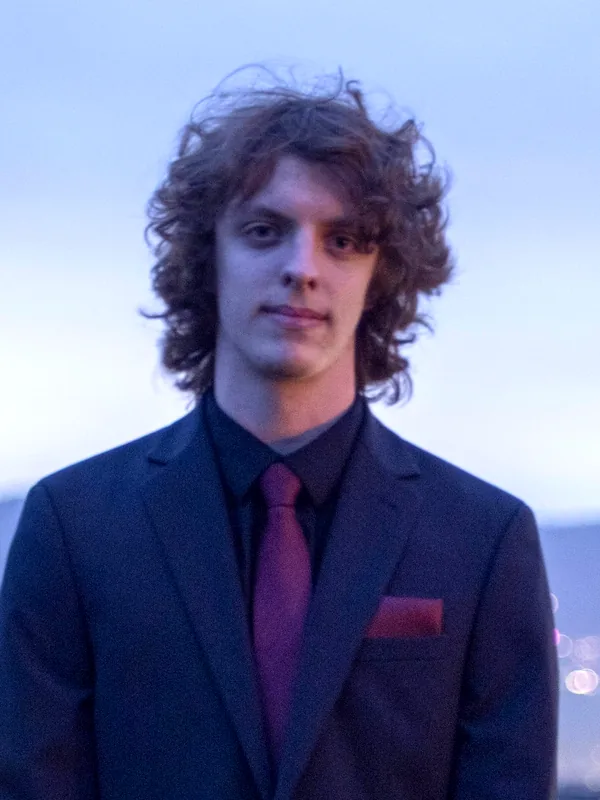 Anthony in a navy suit and red tie at dusk