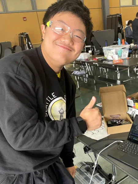 Devyn giving a thumbs up at a workbench